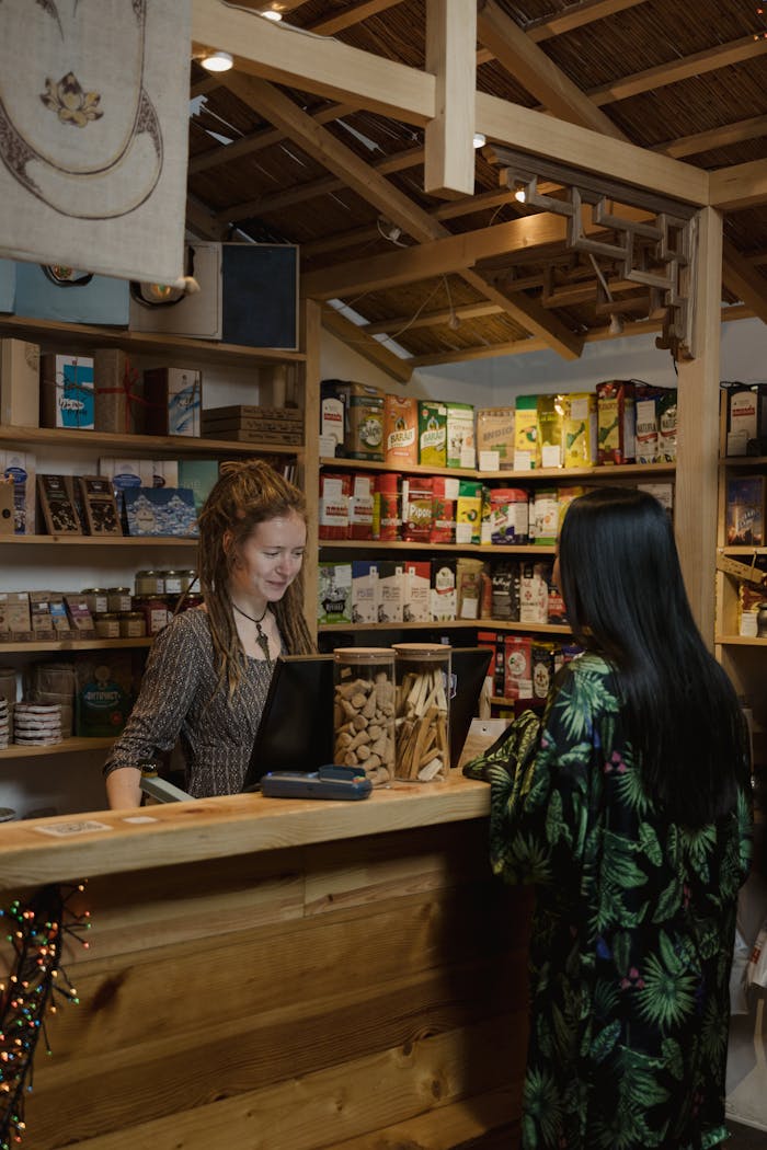 Woman customer interacting at a wood-accented store checkout, surrounded by various merchandise.